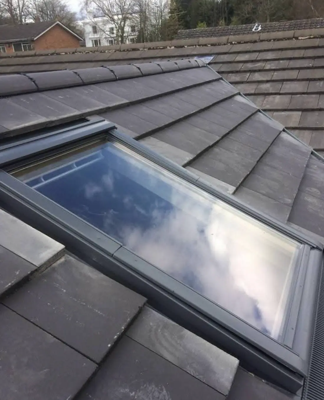 Rooflight fitted into a grey slate roof with grey flashing kit around the frame