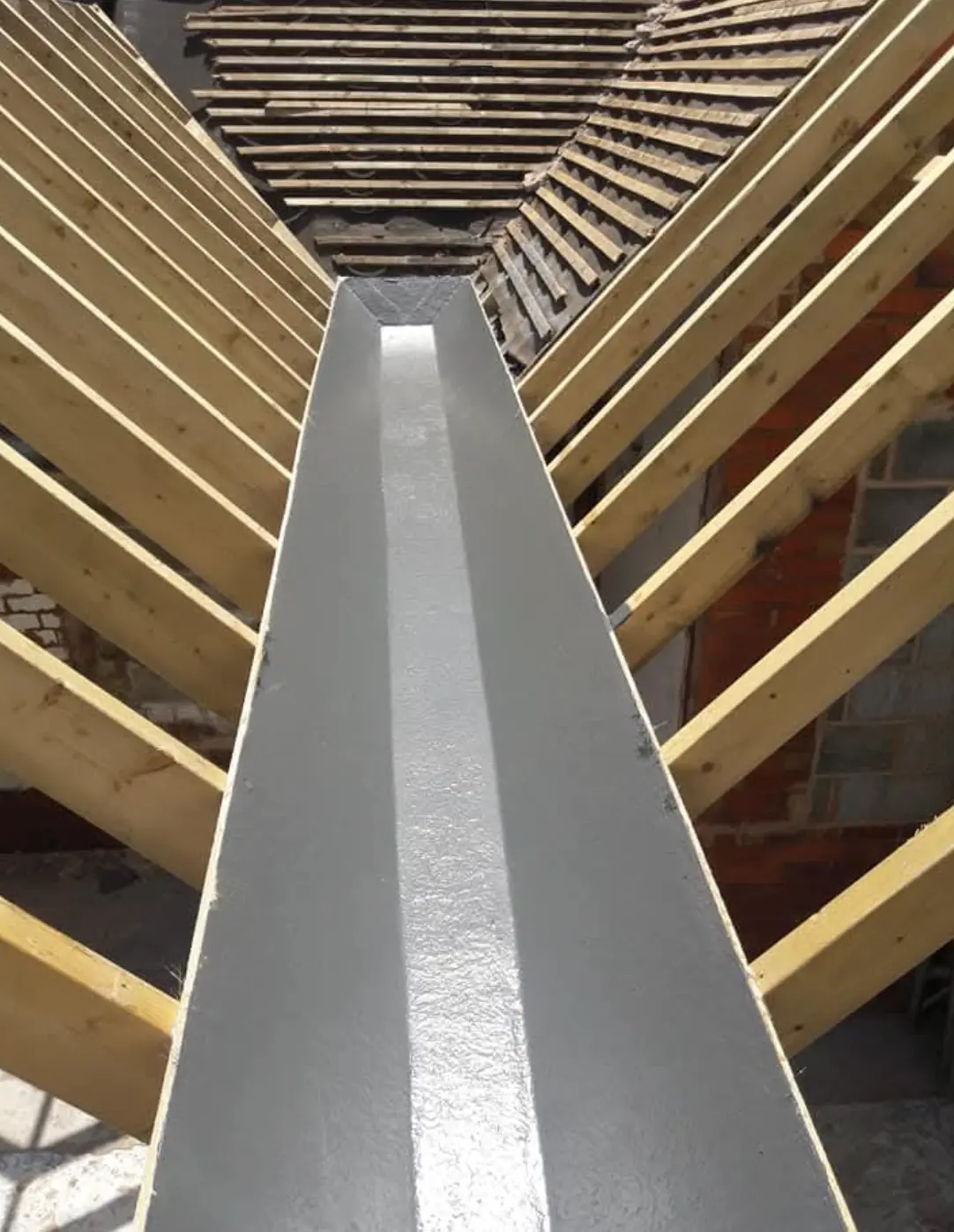Lined box gutter running between two roof slopes with new timber rafters either side
