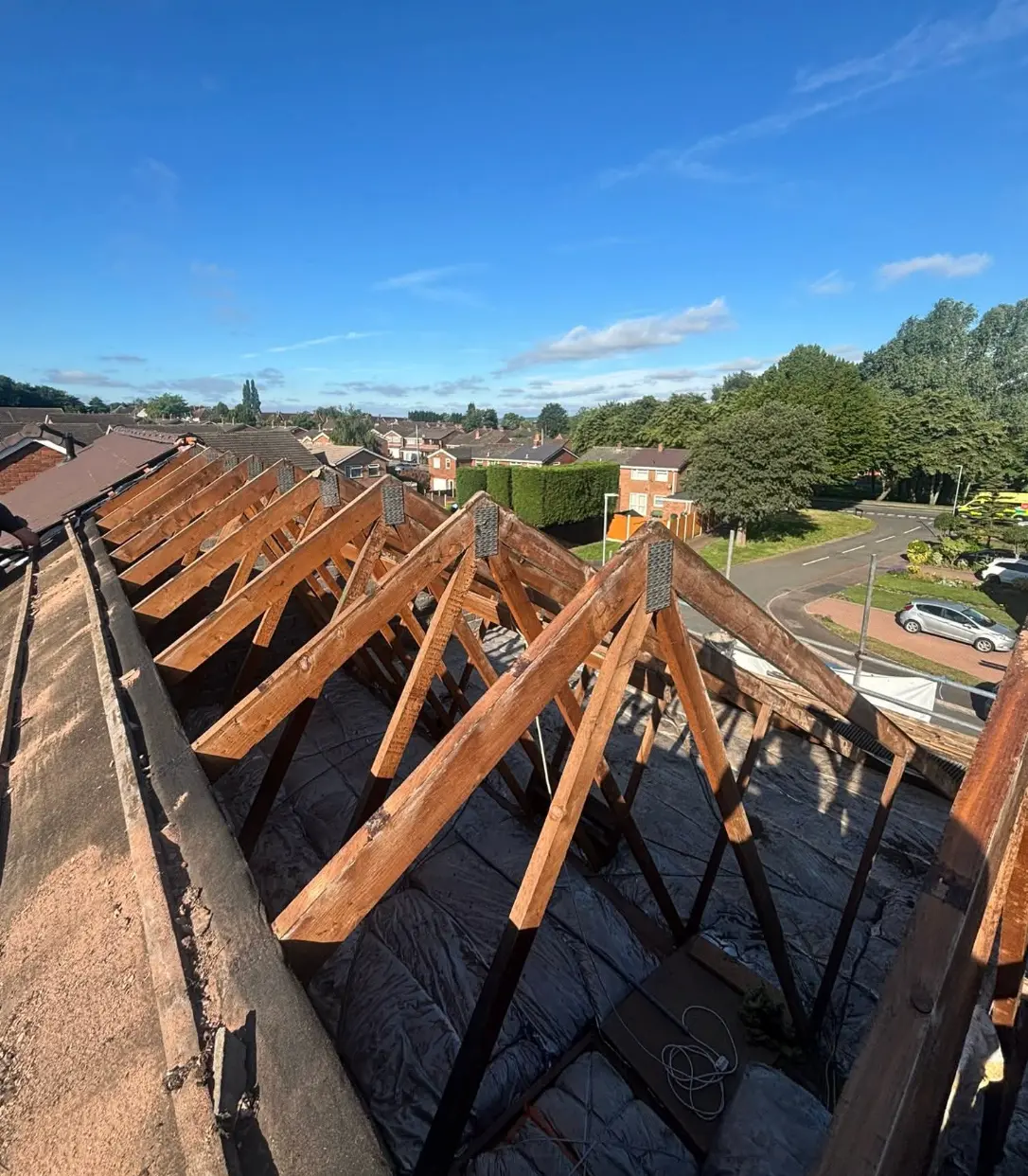 Roof stripped back to bare timber trusses with a view over neighbouring houses