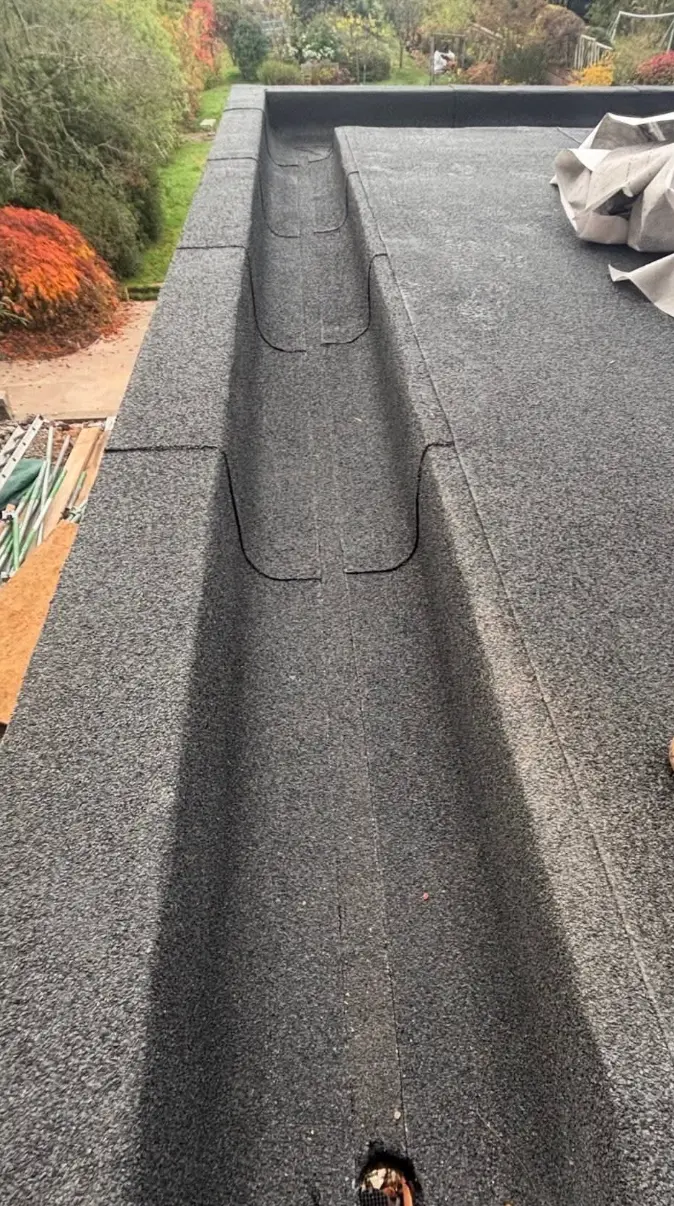 Grey felt flat roof with a central box gutter running to an outlet