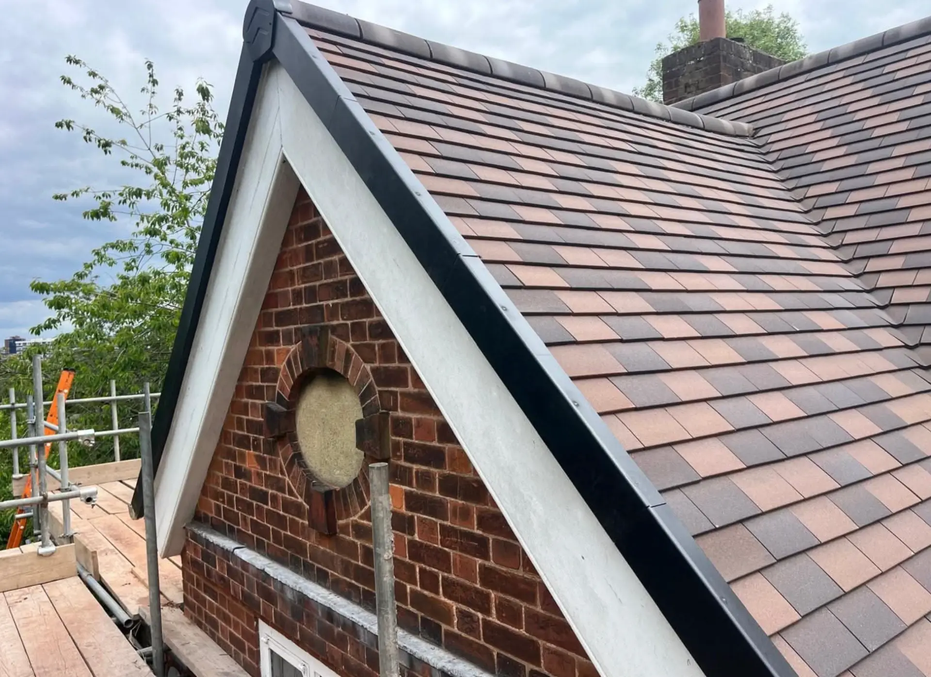 Gable end of a newly tiled roof with black dry verge system fitted along the edge