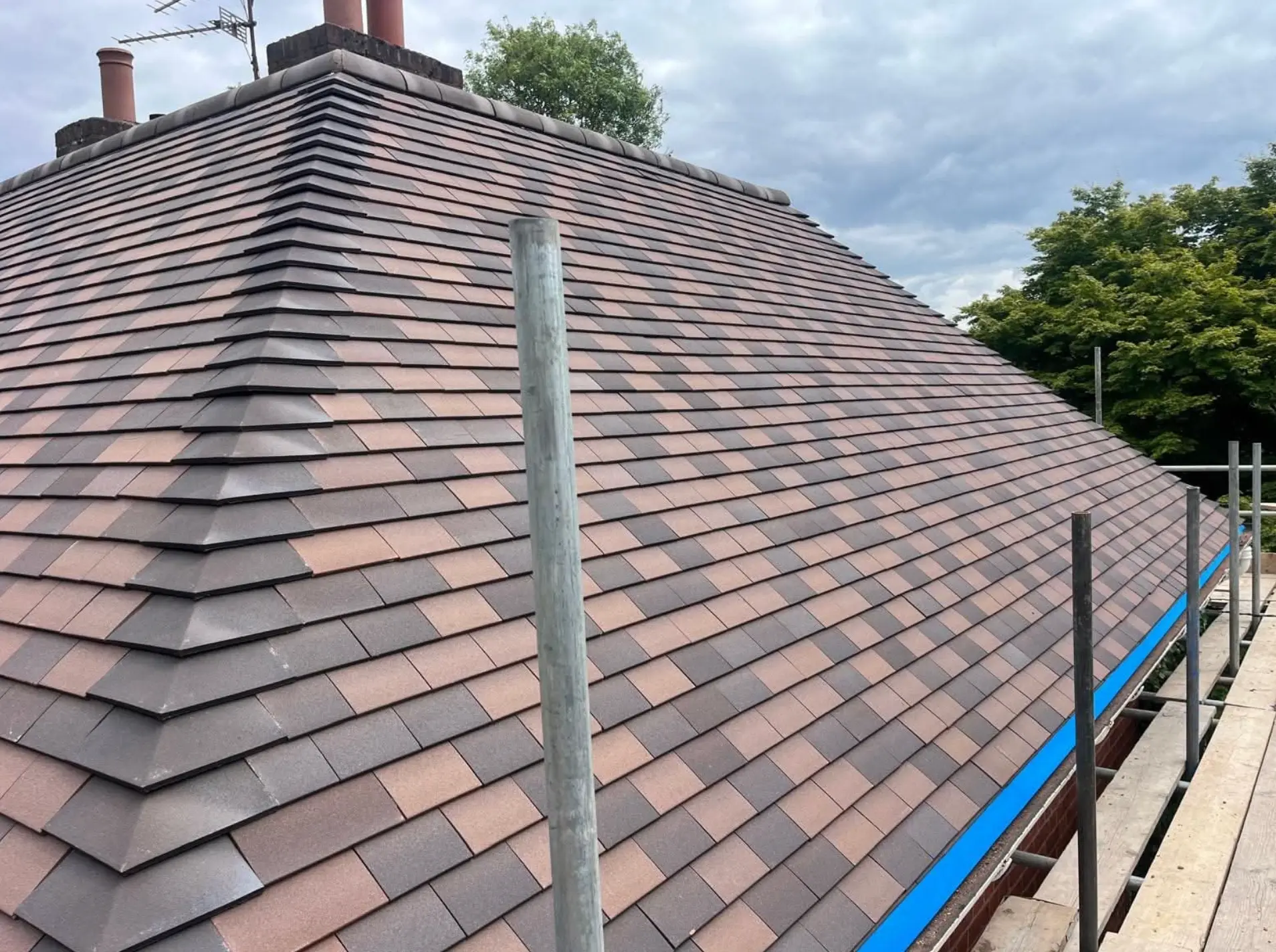 Newly tiled hipped roof with new hip and ridge tiles and original chimney stack
