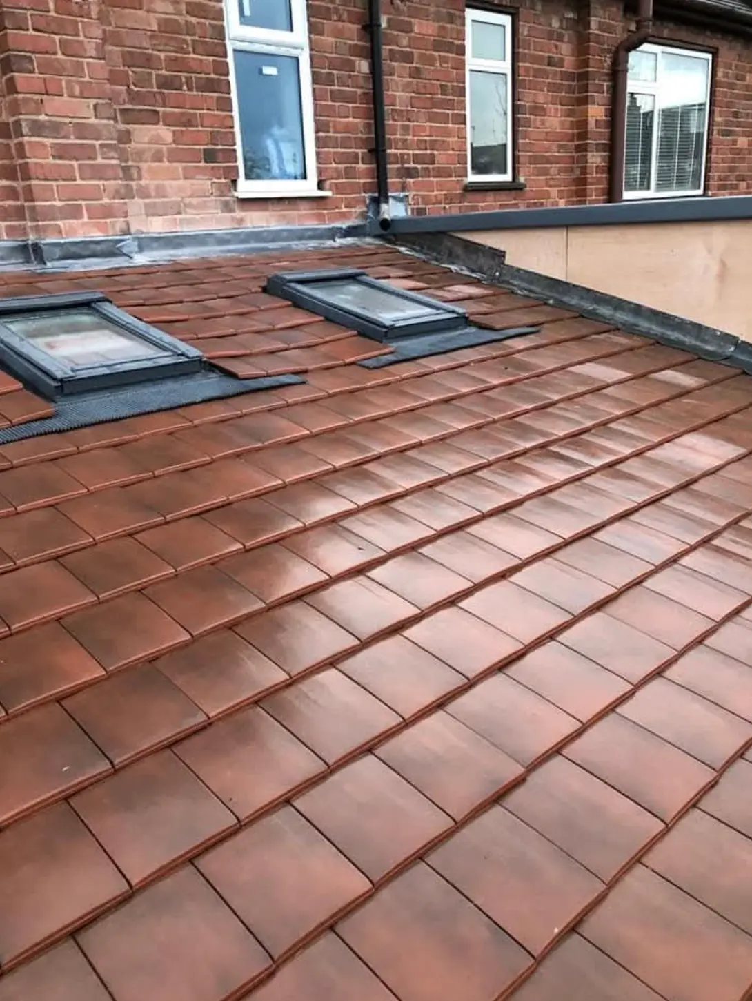 New red clay tiled roof with two rooflights and lead flashing around each opening
