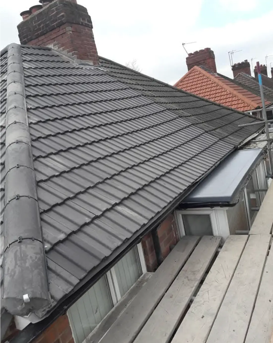 Grey tiled roof on a terraced house with newly bedded ridge and chimney stack